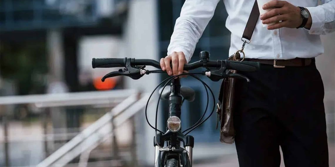 Grupo de ciclistas y peatones cruzando una calle arbolada en ciudad europea