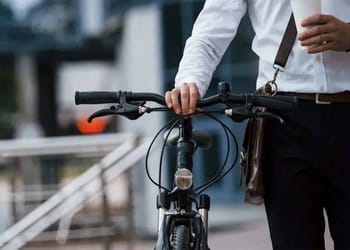 Grupo de ciclistas y peatones cruzando una calle arbolada en ciudad europea