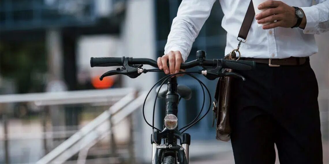 Grupo de ciclistas y peatones cruzando una calle arbolada en ciudad europea