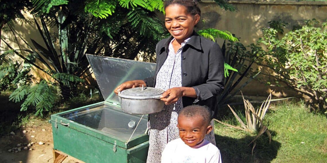 familia cocinando con una cocina solar parabólica casera en el jardín