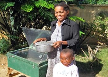 familia cocinando con una cocina solar parabólica casera en el jardín