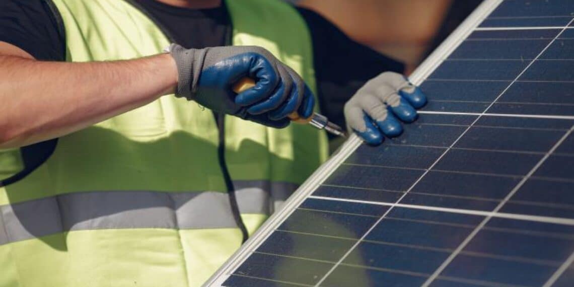 Operario desmontando panel fotovoltaico y separando electrónica con imanes y vidrio.
