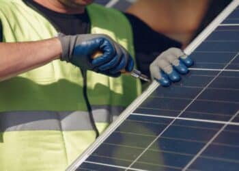 Operario desmontando panel fotovoltaico y separando electrónica con imanes y vidrio.