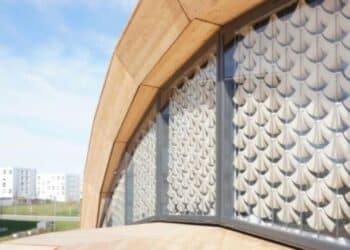 Módulos de arquitectura 4D impresa curvándose al sol en una fachada adaptativa.