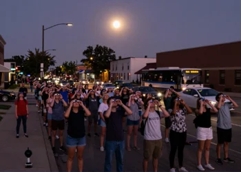 Millones de personas se detuvieron a la vez durante el eclipse de 2024 — y el suelo bajo sus pies lo delató 9 Crowd stands still during the 2024 solar eclipse in an American city, captured with twilight hues and seismograph detail.