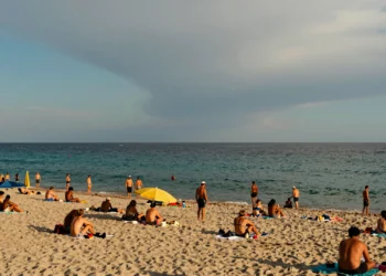 Playa de la Costa Azul con bañistas ajenos a una amenazante pared de agua que se alza en el horizonte mediterráneo