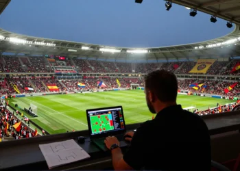 España campeona, Portugal eliminado en grupos y Noruega en semifinales: así luce el Mundial 2026 según este análisis humano 1 Analista frente a un portátil con gráficos tácticos en un estadio del Mundial 2026 abarrotado de aficionados