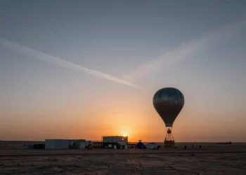 Empresas ya venden «créditos de enfriamiento» y manipulan la atmósfera sin que ninguna ley del mundo pueda detenerlas 7 Globo meteorológico asciende sobre instalación industrial en desierto al atardecer con cielo manipulado por aerosoles