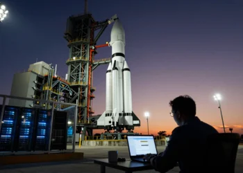 Un análisis de Morningstar valora SpaceX a la mitad de su IPO ignorando sus negocios más lucrativos 2 Analista financiero frente a un ordenador con gráficos, eclipsado por una enorme torre de lanzamiento de cohetes al atardecer