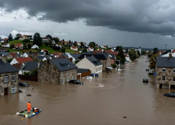Ciudad europea inundada con trabajador de emergencias en balsa, reflejando los daños climáticos de 822.000 millones en Europa