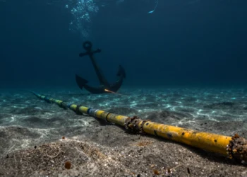 Cable submarino de fibra óptica en el lecho marino con un ancla amenazante y luz difusa desde la superficie