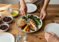 Mujer preparando un plato mediterráneo equilibrado con cereales integrales, verduras asadas y pescado a la plancha