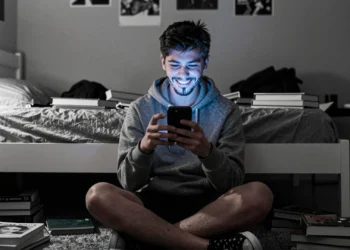 Los niños esquivan las prohibiciones de redes sociales y eso revela el fracaso de las restricciones por edad 7 Adolescente con barba falsa usa el móvil en su habitación, desafiando las restricciones de edad en redes sociales.